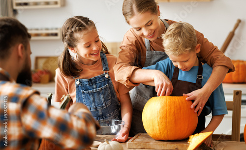 Happy family mother, father and kids  to remove pulp from from pumpkin while carving jack o lantern with family