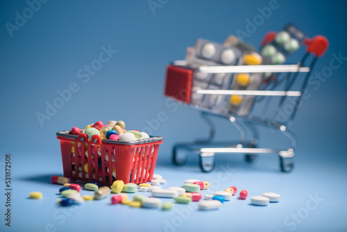 Buy medicine. Shopping basket with various medicinal, pills, tablets on blue background. Studio Photo