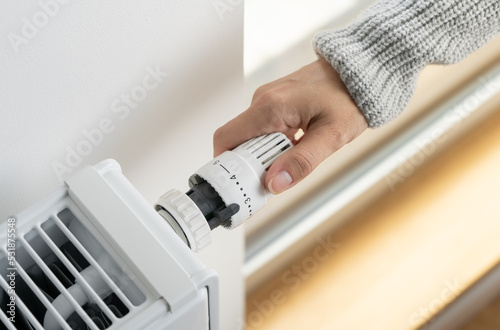 Photography A woman adjusts the radiator thermostat to the economical mode of room heating