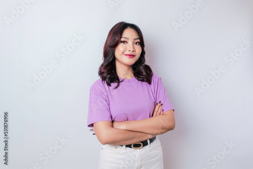 Portrait of a confident smiling Asian woman standing with arms folded and looking at the camera isolated over white background