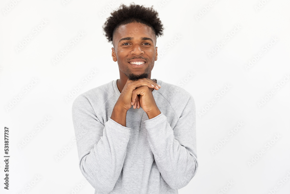 Portrait of interested African American man smiling at camera. Young bearded guy wearing white sweater looking at camera against white background. Curiosity concept