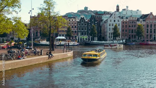 wide shot yellow tourist boat in Amstel canal belt central of Amsterdam summer photo