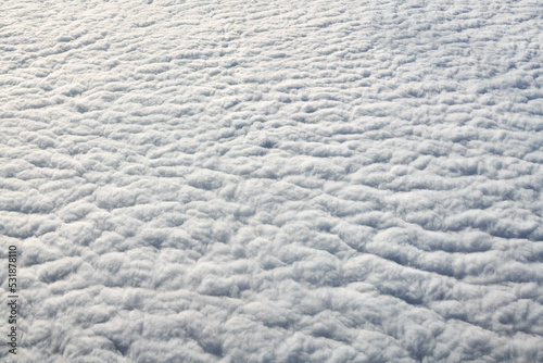 Breathtaking over clouds view from aircraft window, thick white blue clouds looks like soft foam, overcast with fresh frosty air. Beautiful cloudy sky view to troposphere, heavy cloudiness photo