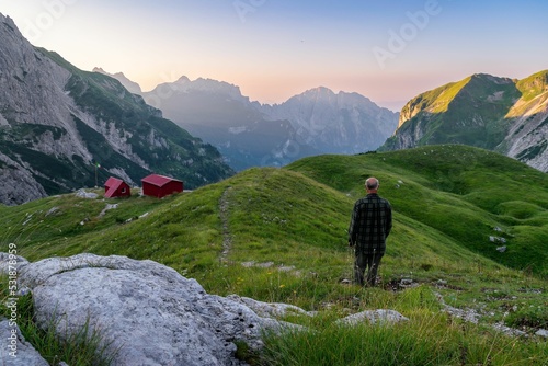 Hiker near shacks in Val Canzoi, bivacco Feltre Walter Bodo, Alps