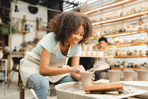 Bild auf Leinwand Creative afro American young woman artist molding clay on pottery wheel, Worksho