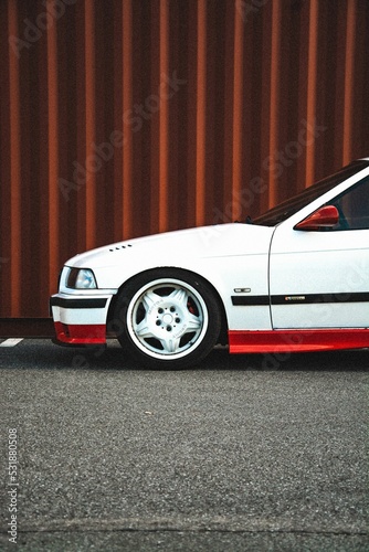 Vertical side shot of a white BMW E36 hood on the red background