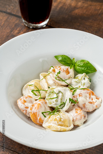 different types of pelmeni or russian dumplings in white plate on wooden background