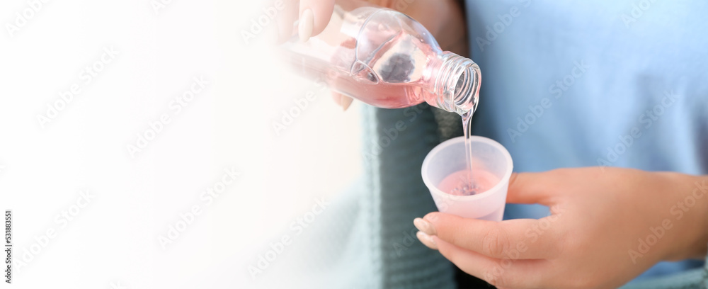 Woman pouring cough syrup from bottle into cup, closeup. Banner for design Woman pouring cough syrup from bottle into cup, closeup. Banner for design