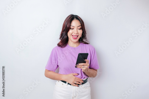Pleased smiling Asian woman keeps hand on belly feels happy after ordering food by phone