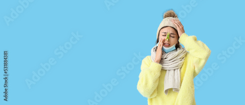 фотографія Ill young woman with clothespin on her nose against blue background with space f