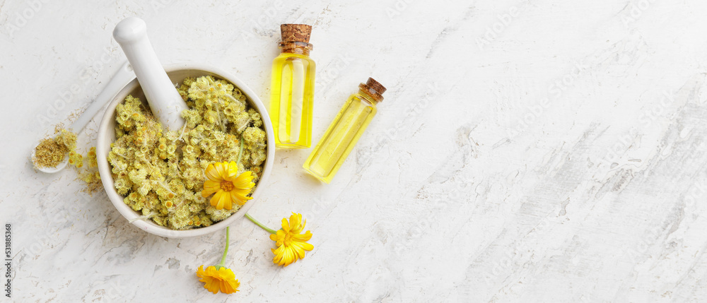 Mortar with dry herbs and bottles of essential oil on light background with space for text Mortar with dry herbs and bottles of essential oil on light background with space for text