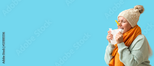 Ill mature woman with clothespin on her nose against blue background with space for text