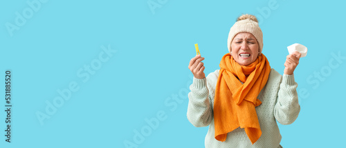 Foto Stressed mature woman with clothespin and tissue on blue background with space for text