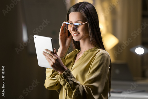 Smiling businesswoman with tablet computer working in office at night
