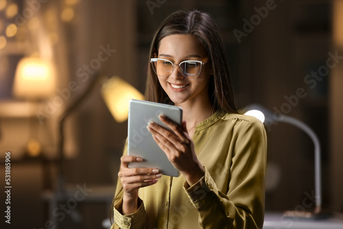 Smiling businesswoman with tablet computer working in office at night