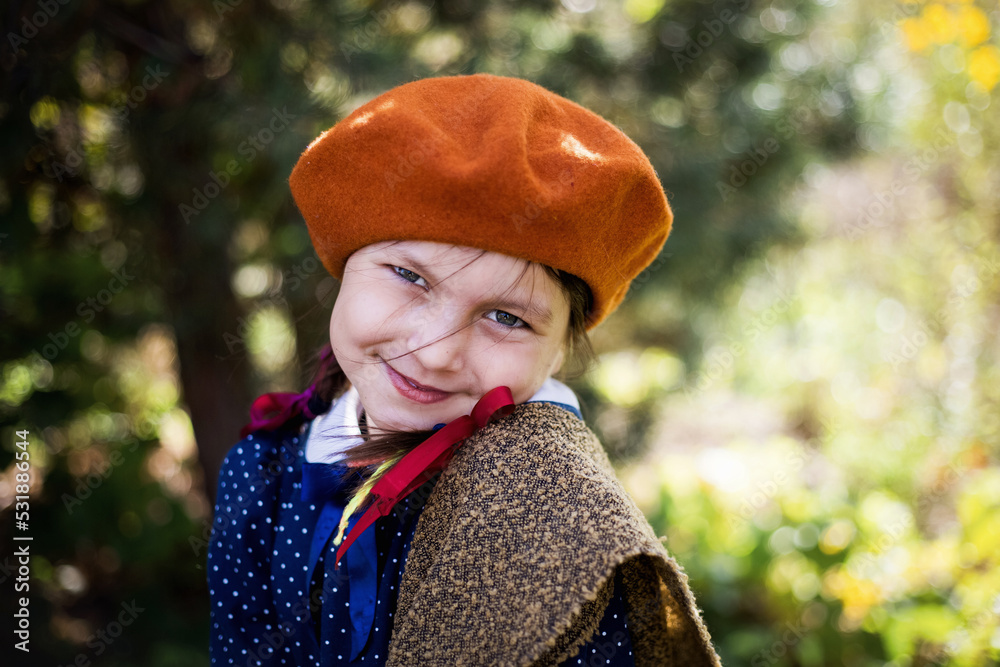 Dziewczynka w berecie i jesiennych barwach trzyma wielką dynię - obrazy, fototapety, plakaty 