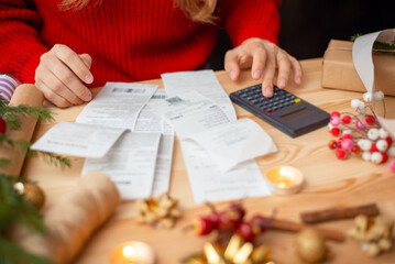 Close-up shot of checks, bills and receipts on wooden table and girl counting them. Concept of much spends on Christmas holidays celebration, money on presents and decorations