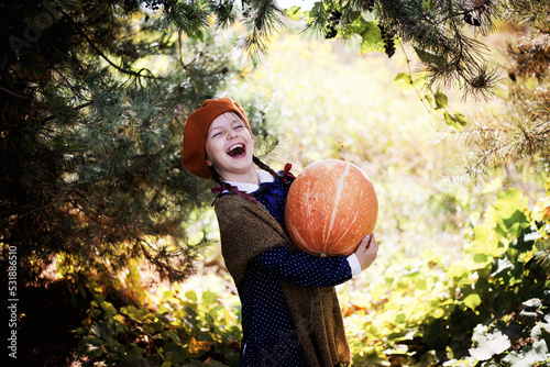 Dziewczynka w berecie i jesiennych barwach trzyma wielką dynię