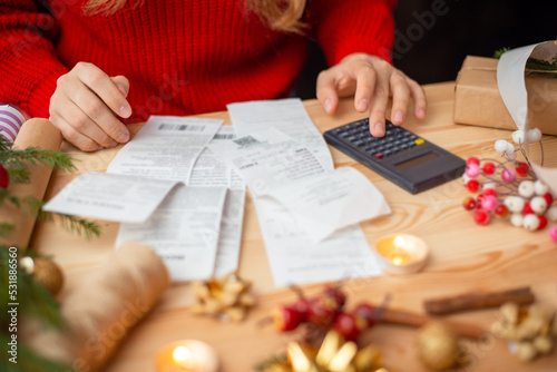 Close-up shot of checks, bills and receipts on wooden table and girl counting them. Concept of much spends on Christmas holidays celebration, money on presents and decorations