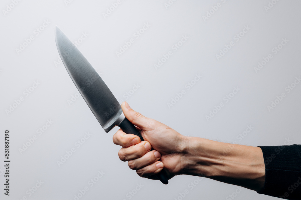 Male hand holding a huge sharp knife. Isolated on white background Male hand holding a huge sharp knife. Isolated on white background