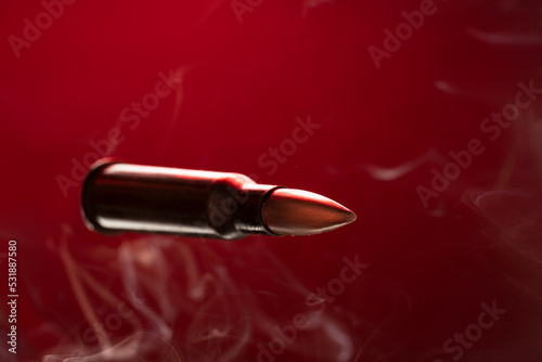 Rifle bullet in smoke on red background.