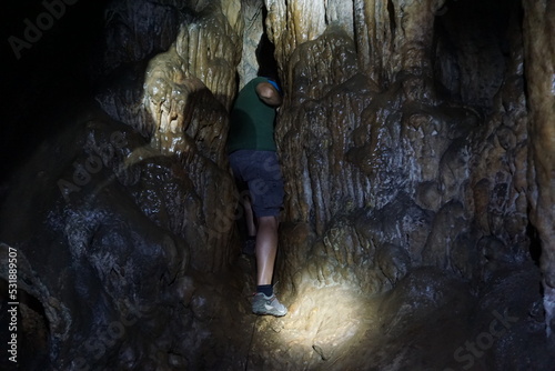 Esploratore in una grotta carsica a Pantalica in Sicilia, mentre passa attraverso due colonne strette photo