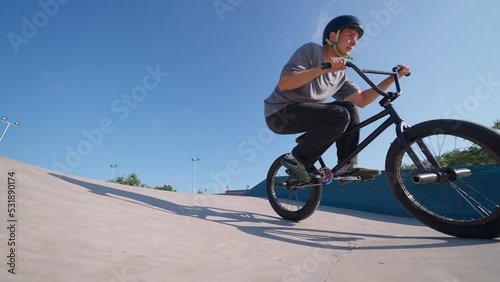 A professional cyclist rides and performs tricks on bmx. Beautiful stunts and bike jumps in the park on a concrete platform with obstacles. Man.

