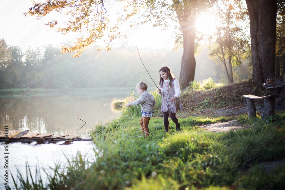 Obraz premium Rodzeństwo bawi się w parku w promieniach jesiennego słońca