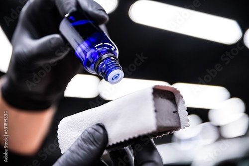Obraz na płótnie employee of the car detailing studio applies a ceramic coating to a special applicator to protect and protect the car paintwork w salonie