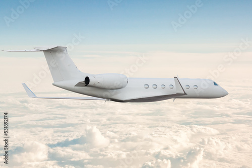 White modern luxury executive aircraft flies in the air above the clouds