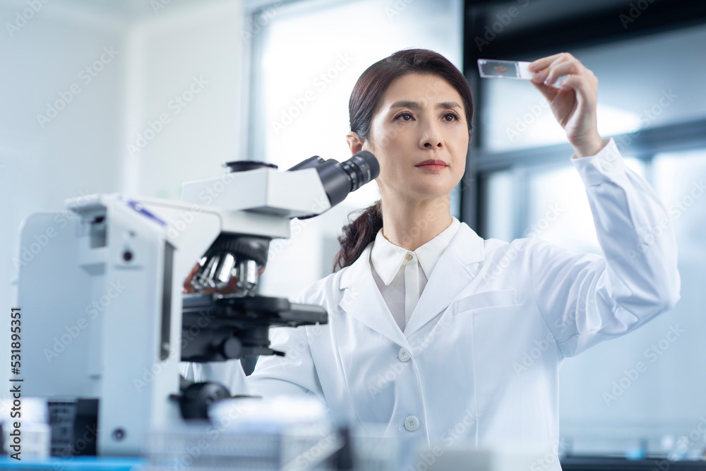 Scientist looking at a microscope slide Scientist looking at a microscope slide