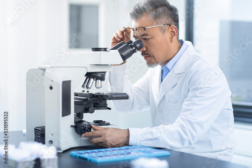 Scientist looking through a microscope photo