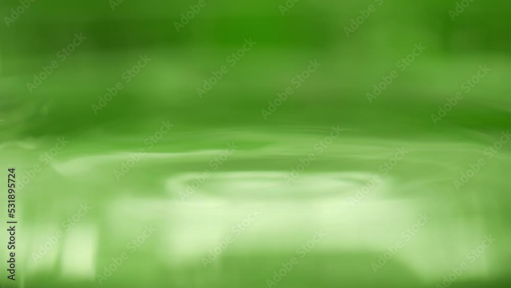 Drop is falling into green liquid. Crystal clear water splash. Concept of natural springs and wellness or beauty products. Green tea or aloe vera extract. Cold mineral water in slow motion
