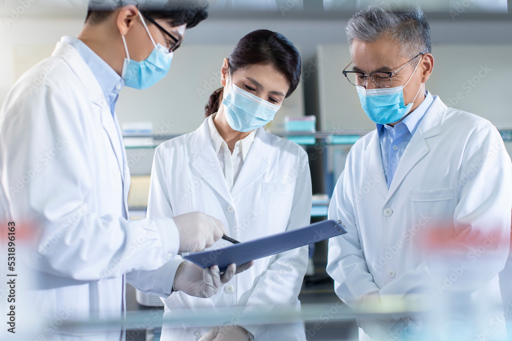Three researchers discussing in laboratory Three researchers discussing in laboratory