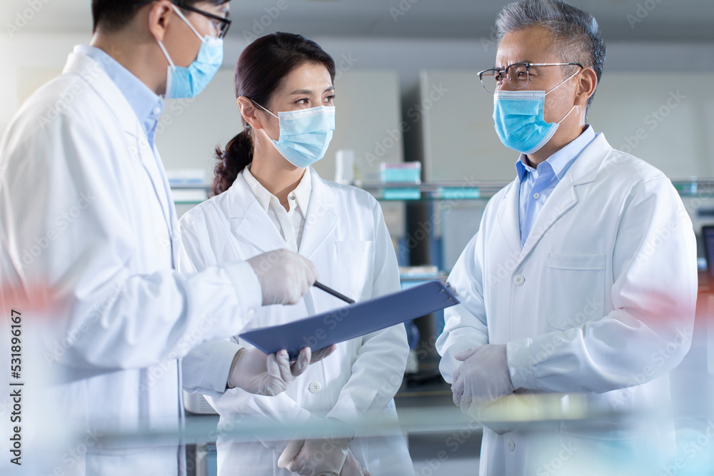 Three researchers discussing in laboratory Three researchers discussing in laboratory