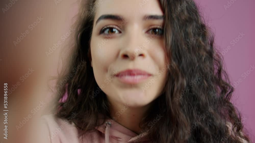 Close-up of excited young lady speaking looking at camera during video call on pink background. People and communication concept. Close-up of excited young lady speaking looking at camera during video call on pink background. People and communication concept.