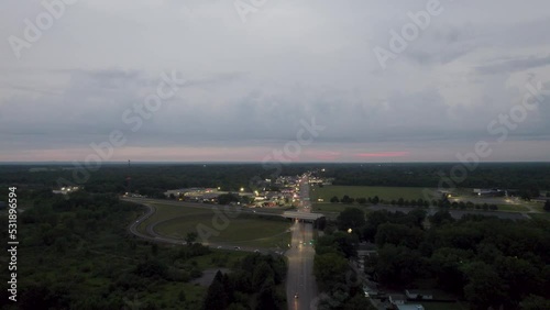 Aerial drone shot over a highway with narrows lanes with small homes on both sides of a road at sunset.
 photo