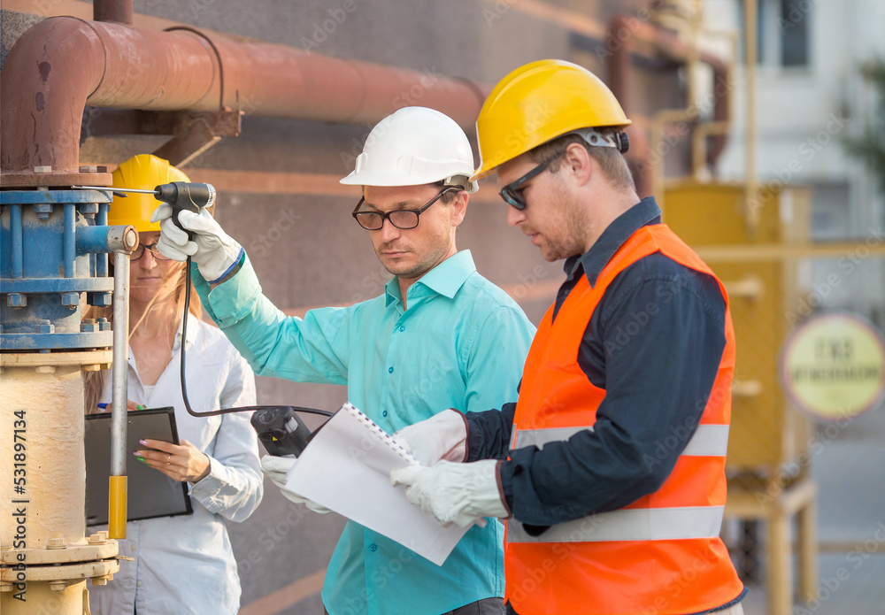 young-men-and-a-woman-are-standing-near-a-gas-pipe-with-an-analyzer-and