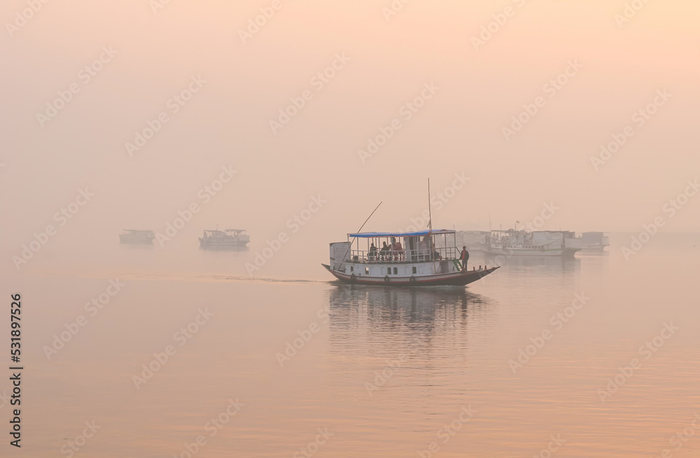 Boats in a foggy lagoon at sunrise.