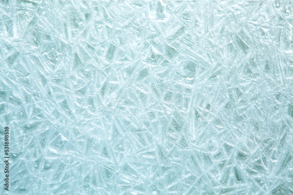 The texture of the ice surface. Winter background, festive background in the form of ice crystals, ice background for New Year's card, in a blue tone. The texture of the ice surface. Winter background, festive background in the form of ice crystals, ice background for New Year's card, in a blue tone.