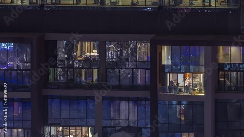 Flat night panorama of multicolor light in windows of multistory buildings with gym aerial timelapse. Illuminated skyscraper in a big city photo