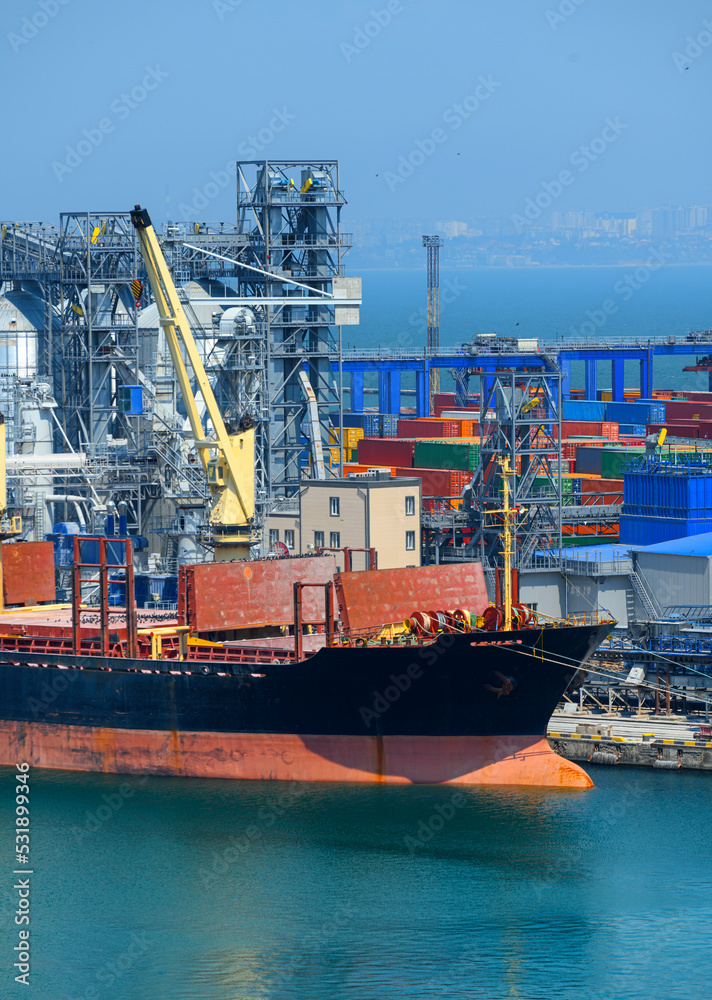 industrial seaport infrastructure, sea, cranes and dry cargo ship, grain silo, bulk carrier vessel and grain storage elevators, concept of sea cargo transportation