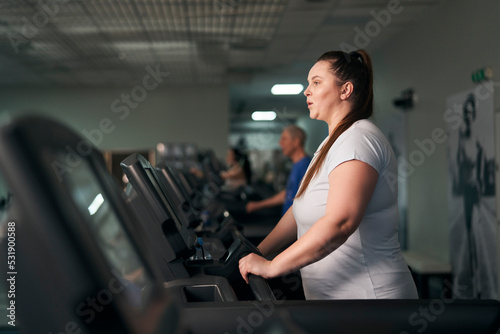Plus size caucasian woman running on treadmill at gym