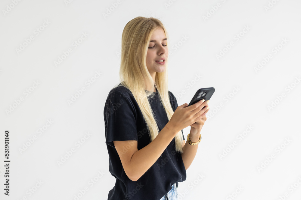 Pleased woman in t-shirt writing message on smartphone over white background Pleased woman in t-shirt writing message on smartphone over white background