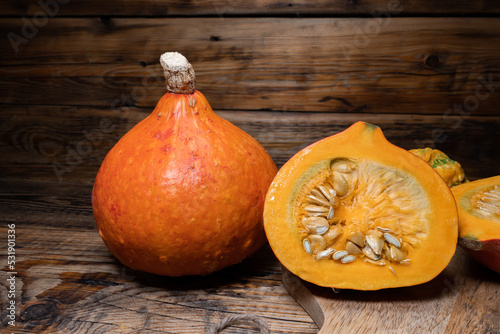 Hokkaido pumpkins on wooden background. Red kuri squash autumn fall rustic composition for Halloween or Thanksgiving. photo