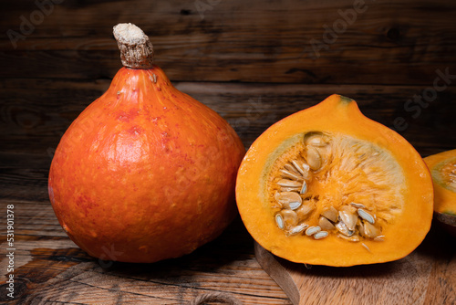 Hokkaido pumpkins on wooden background. Red kuri squash autumn fall rustic composition for Halloween or Thanksgiving. photo