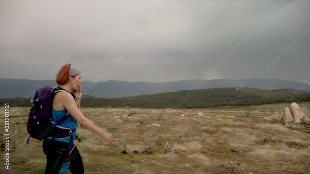 A shot of a businesswoman talking on the phone while walking on top of a mountain range, paying no attention to landscape. A shot of a businesswoman talking on the phone while walking on top of a mountain range, paying no attention to landscape.