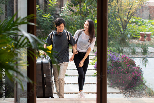 Happy young couple entering hotel room with suitcase