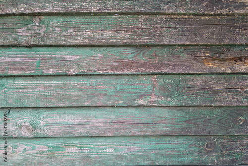 The texture of an old wooden fence with stripped paint. An old shabby wooden fence. Rough wood texture.