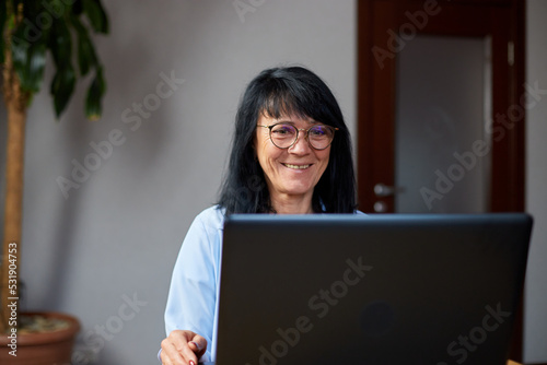 Happy mature older woman conference calling in video chat meeting on laptop